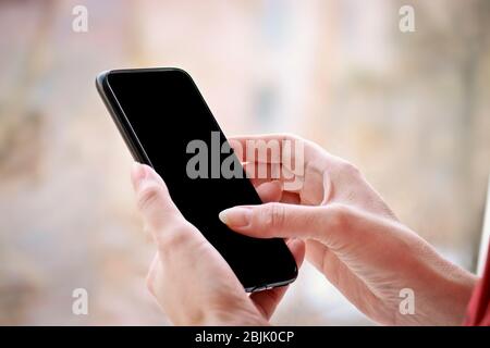 Female hand with smartphone, black blank screen with copy space. Stock Photo