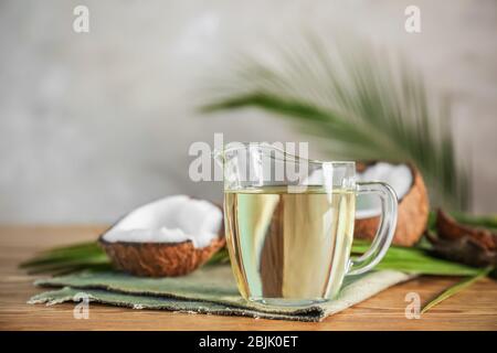 Pitcher with coconut oil on wooden table Stock Photo