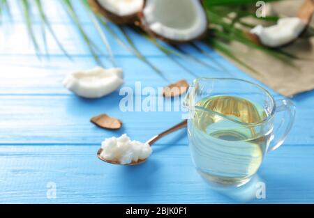 Pitcher with coconut oil on color wooden background Stock Photo