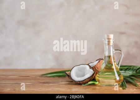 Ripe coconut and pitcher with oil on wooden table Stock Photo