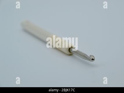 Close up vintage cream crochet hook in macro on a white background Stock Photo