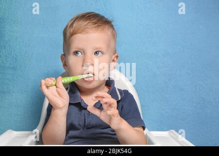 Adorable little boy brushing teeth on color background Stock Photo