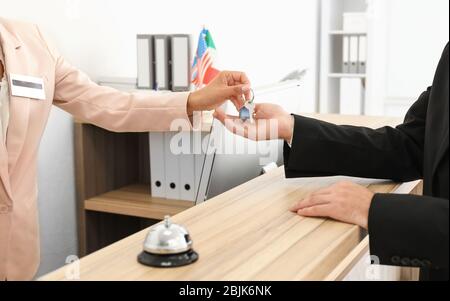 Female receptionist handing room key to customer in hotel Stock Photo