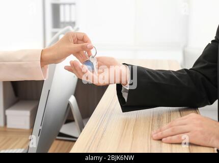 Female receptionist handing room key to customer in hotel Stock Photo