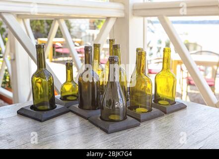 Many candle holders made from wine bottles on wooden table Stock Photo