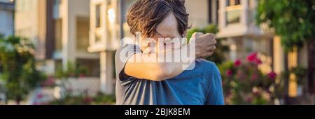 How to sneeze correctly. Man sneezes on the elbow. Concept of the spread of the virus BANNER, LONG FORMAT Stock Photo