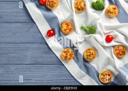 Composition with broccoli quiche tartlets and vegetables on table Stock Photo