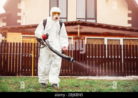 Disinfection of recreation parks from coronavirus virus, worker in protective suit with spray Stock Photo