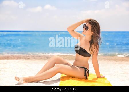 Beautiful young woman sunbathing on sea beach Stock Photo