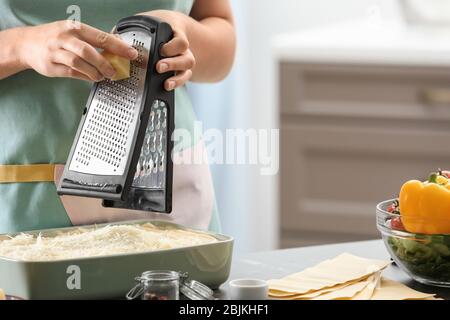 Woman grating cheese for lasagna in kitchen Stock Photo