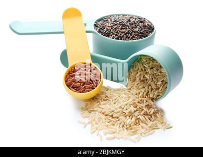 Different types of rice in measure scoops on white background Stock Photo