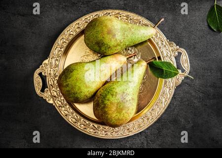 Ornate metal plate with ripe pears on grey background Stock Photo