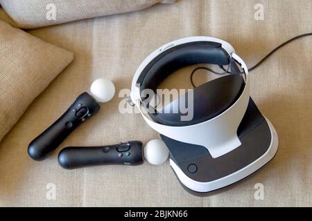 Moscow,Russia - April 12 2020 A playstation 4 VR headset together with a playstation 4 controller and two move controllers on a sofa, ready to start g Stock Photo