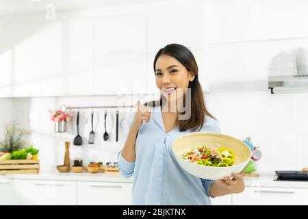 Young Woman Cooking in the kitchen. Healthy Food - Vegetable Salad Diet. Healthy Lifestyle. Cooking delicious food during the COVID-19 self-quarantine Stock Photo