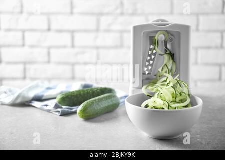 Spiral vegetable slicer with cucumber spaghetti on table Stock Photo