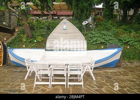 Table with chairs and bench in shape of boat in courtyard of hotel Stock Photo
