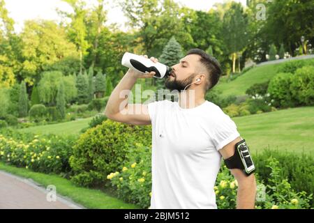 Handsome man drinking water after running outdoors Stock Photo