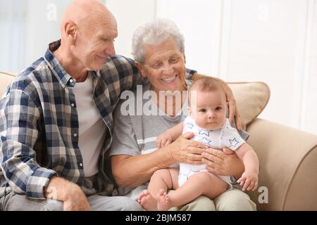 Senior couple with their little grandchild resting at home Stock Photo