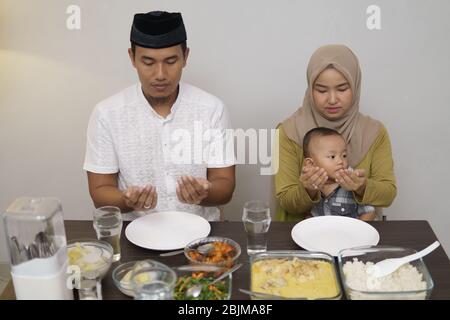 muslim family pray before having dinner together on ramadan Stock Photo
