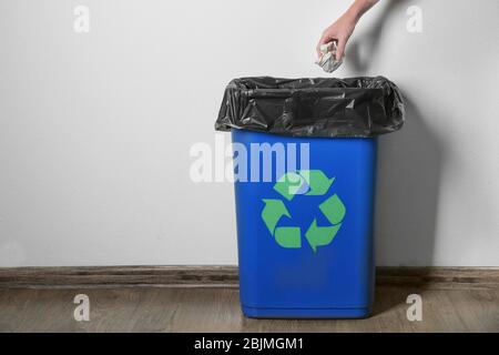 Woman throwing garbage in rubbish bin with logo of recycling in room Stock Photo