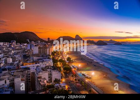 Overview of Avenida Atlantica and Copacabana Beach predawn, with Sugarloaf Mountain in background, Rio de Janeiro, Brazil.
