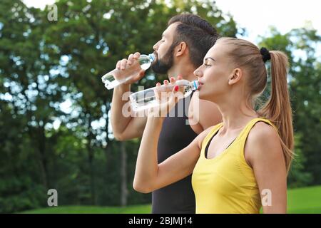 Young sporty couple drinking water in green park Stock Photo