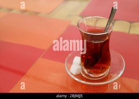 Hot Turkish Tea in Tulip-shaped Glass with Sugar Cubes Isolated on Colorful Luncheon Mats Stock Photo