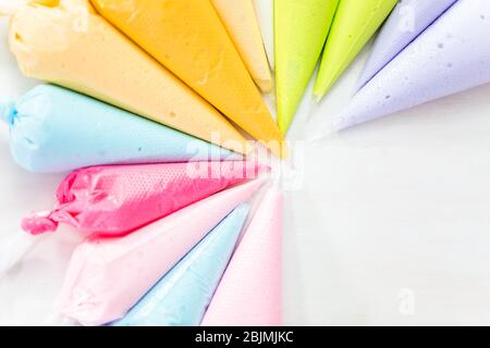 Piping bags with pastel color royal icing to decorate Easter sugar cookies. Stock Photo