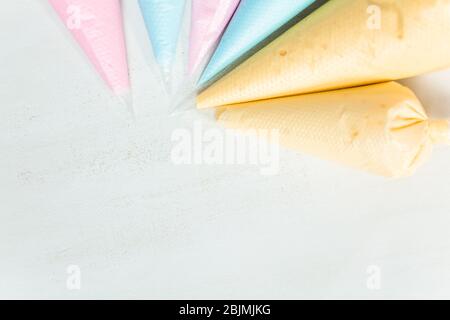 Piping bags with pastel color royal icing to decorate Easter sugar cookies. Stock Photo