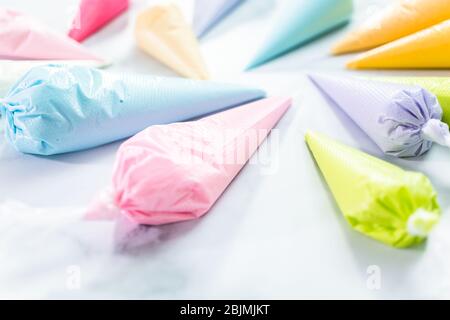 Piping bags with pastel color royal icing to decorate Easter sugar cookies. Stock Photo