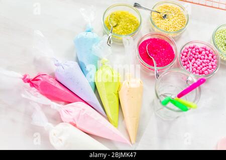 Piping bags with pastel color royal icing to decorate Easter sugar cookies. Stock Photo