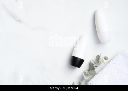 Deodorant bottles mockups with eucalyptus and towel on marble background. Flat lay, top view. Blank antiperspirant packaging, sweat protection product Stock Photo