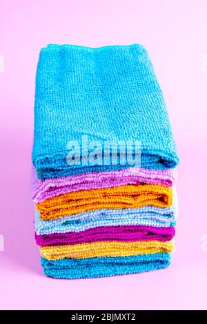 Multi-colored towels on a pink background. Pink, beige, yellow, orange and blue towels. House order Stock Photo
