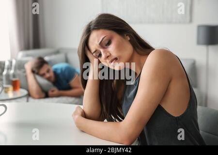 Battered woman and drunk man on sofa at home Stock Photo