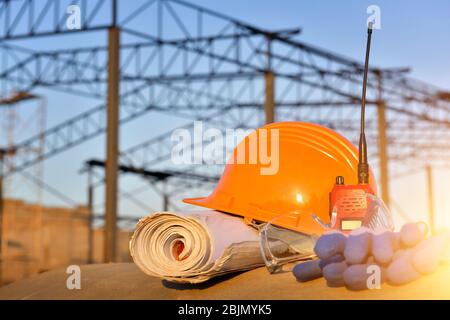 Hard hat, walkie talkie, blueprint and gloves on a construction site Stock Photo