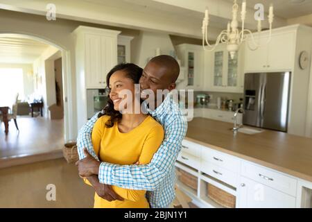 Happy couple hugging each other in their kitchen Stock Photo