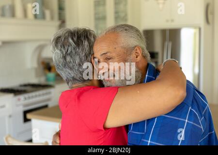 Happy senior couple hugging each other in their kitchen Stock Photo