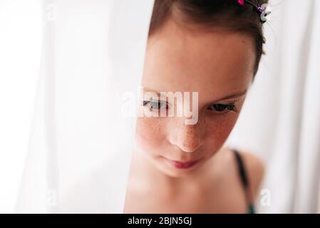 Portrait of a young girl wearing make-up standing by a curtain Stock Photo