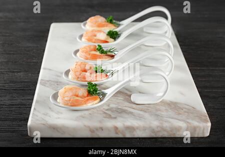 Board with tasty shrimps and white sauce on table Stock Photo