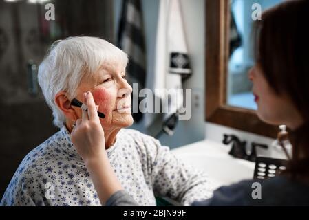 Girl putting make-up on her Grandmother Stock Photo