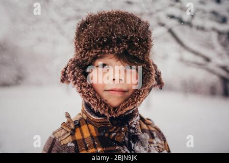 Portrait of a boy wearing a hunters cap in the snow, USA Stock Photo