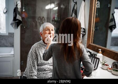 Girl putting make-up on her Grandmother Stock Photo