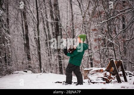 Boy collecting firewood from a woodpile in the garden, USA
