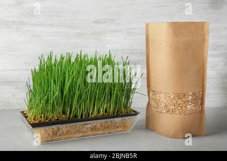 Sprouter with wheat grass and seeds in paper package on table Stock Photo