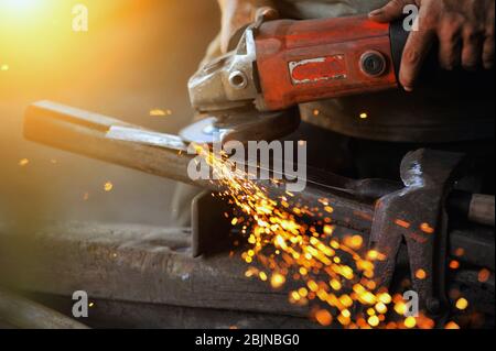 Close-up of a man using a grinder in a workshop, Thailand Stock Photo