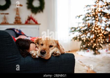 Girl sleeping on a sofa with her dog Stock Photo