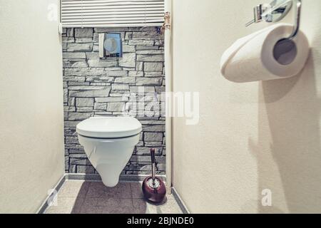 White built in toilet bowl in modern bathroom with paper holder and toilet brush Stock Photo