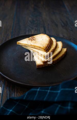 Spicy Circassian Triangle Smoked Cheese Slices on Dark Wooden Plate with Spices. Ready to Eat. Stock Photo