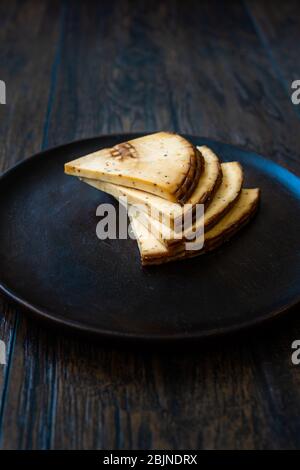 Spicy Circassian Triangle Smoked Cheese Slices on Dark Wooden Plate with Spices. Ready to Eat. Stock Photo