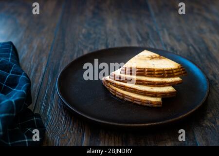 Spicy Circassian Triangle Smoked Cheese Slices on Dark Wooden Plate with Spices. Ready to Eat. Stock Photo